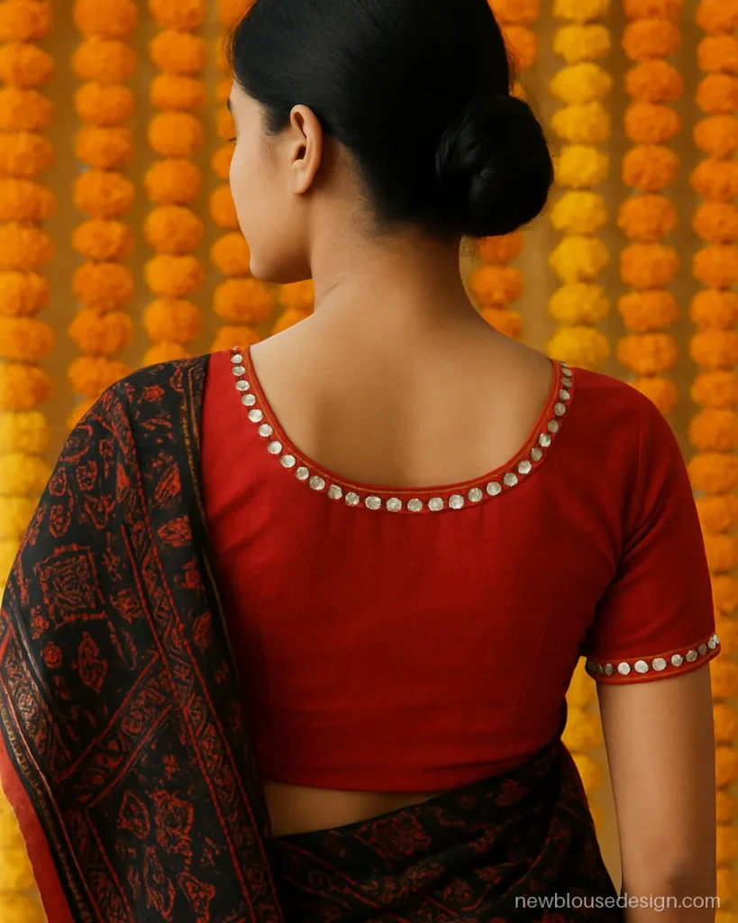 Red cotton blouse with round back neck bordered by small round mirrors and chain stitch