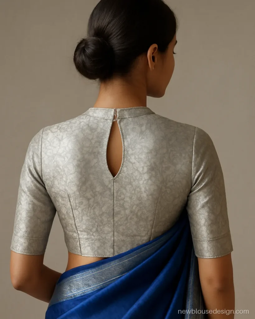 Fancy silver blouse design in silver zari brocade with high neck and keyhole back