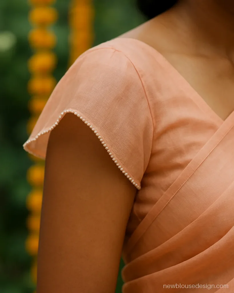 Peach organza blouse with flutter cap sleeves and pearl edging